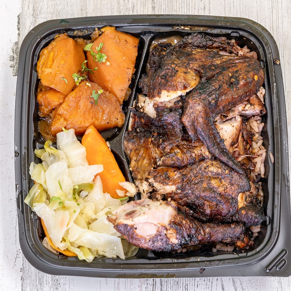 St. Bess Jerk's Jamaican meal with jerk chicken, rice, stewed sweet potatoes, and cabbage.